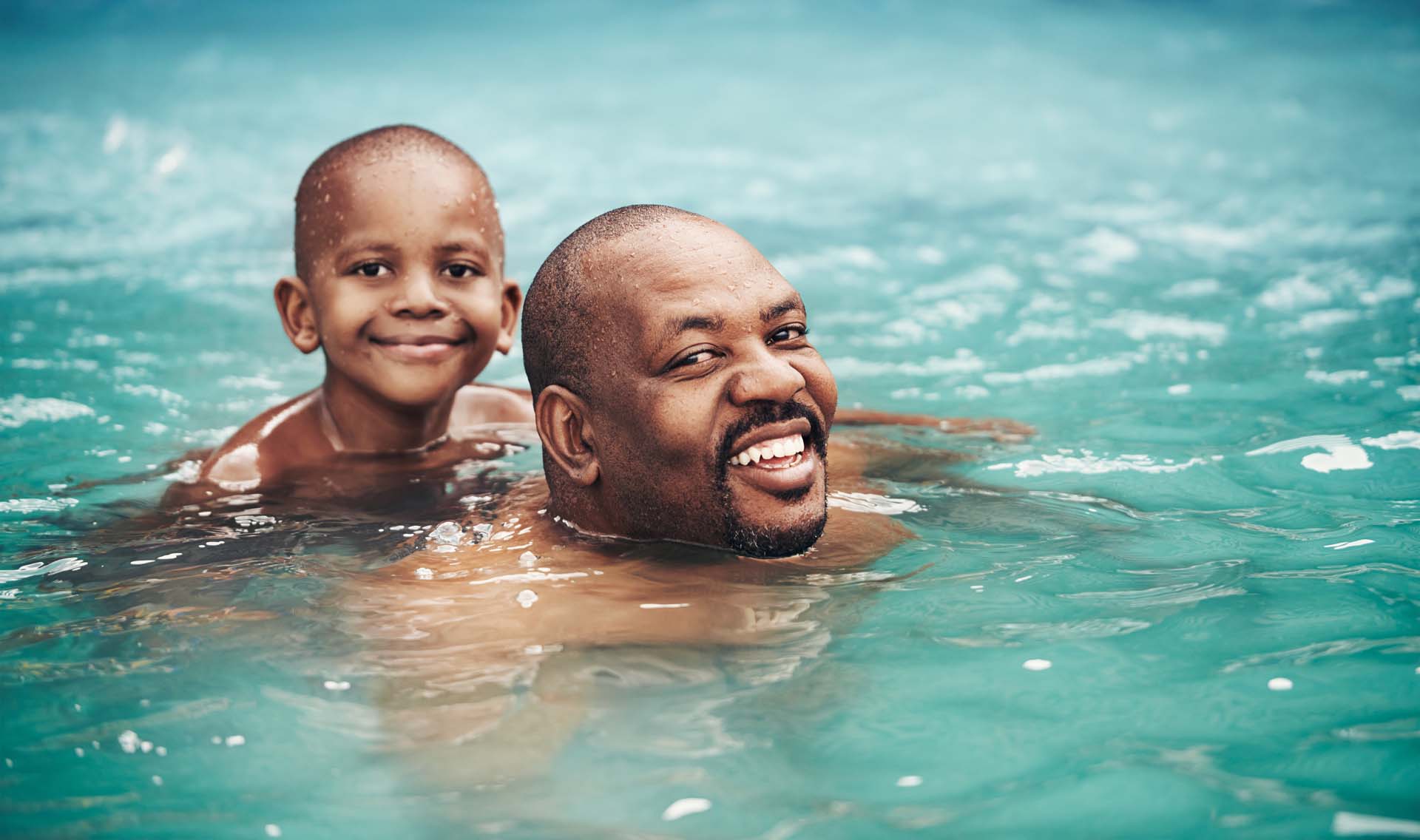 Shot of a happy little boy having fun with his father in a swimming pool